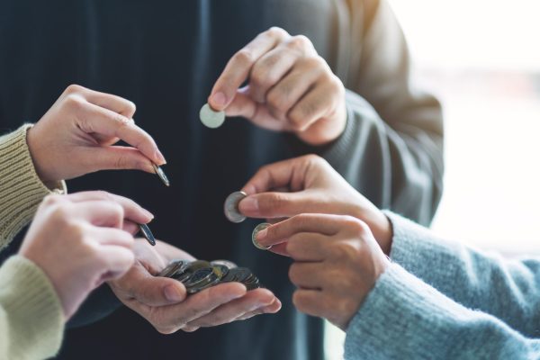 Closeup image of people putting coins into another people's hands