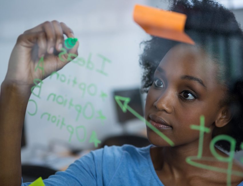 Female graphic designer writing on glass with marker